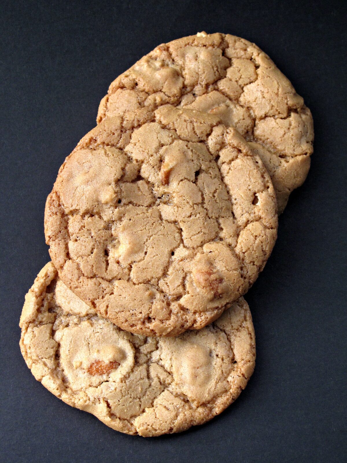 Three cookies with crackled tops closeup on black background.