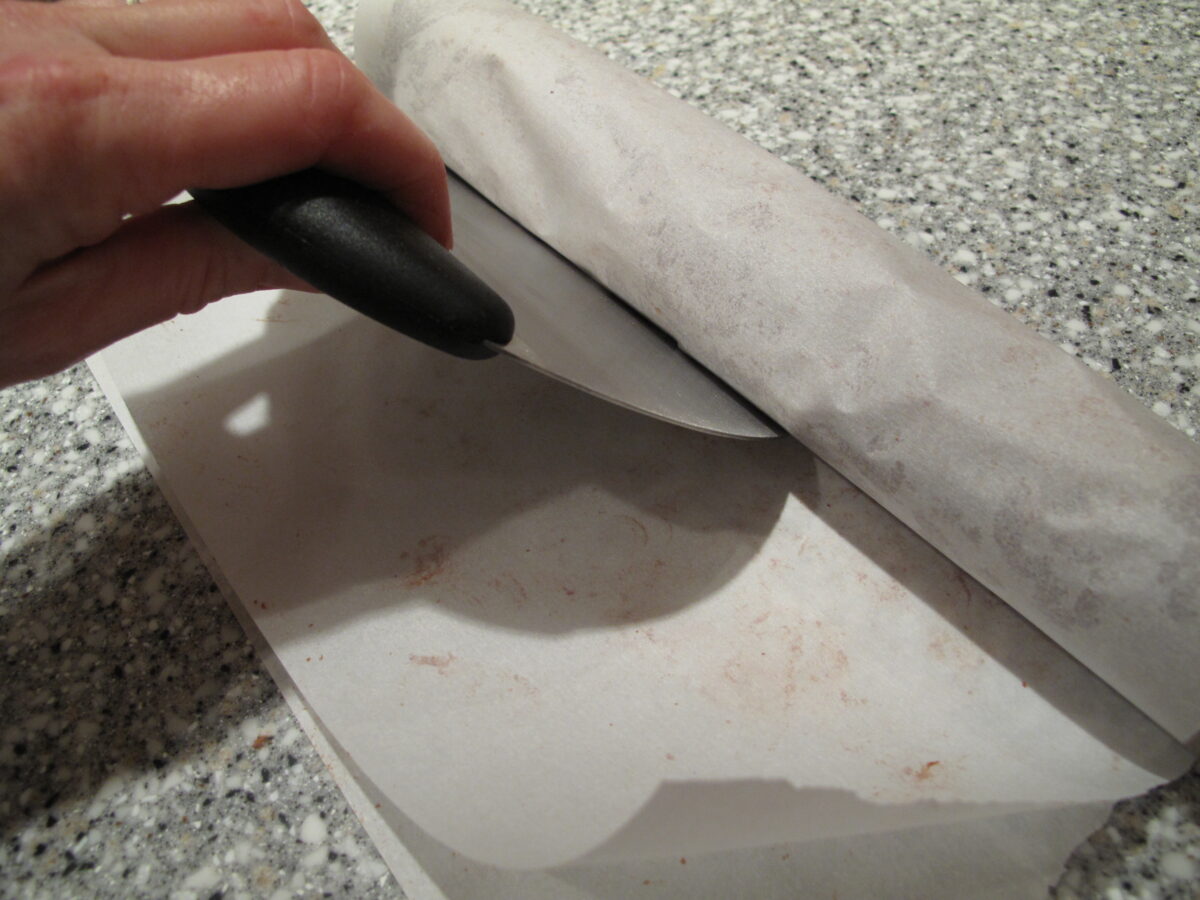 Fold parchment over dough log and use bench scraper pressing firmly at base compressing dough.