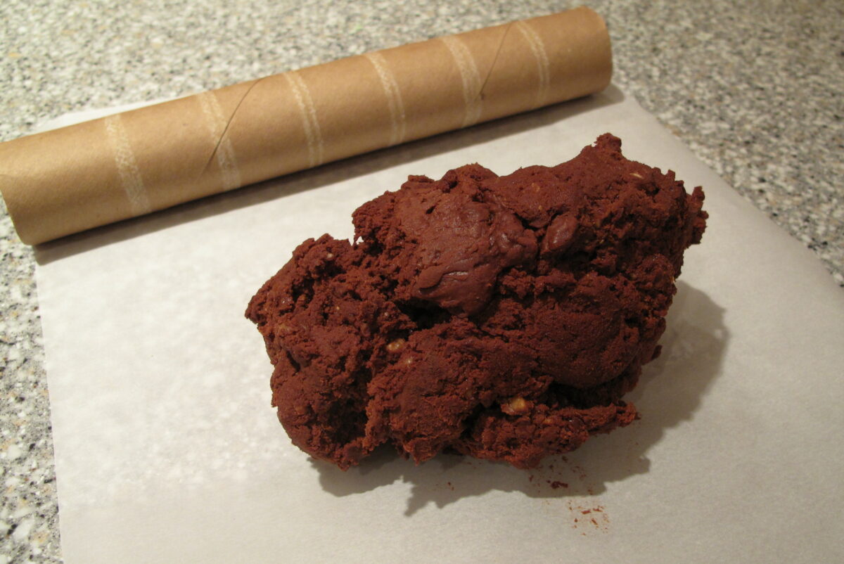 Dough on parchment paper with paper towel tube in background.