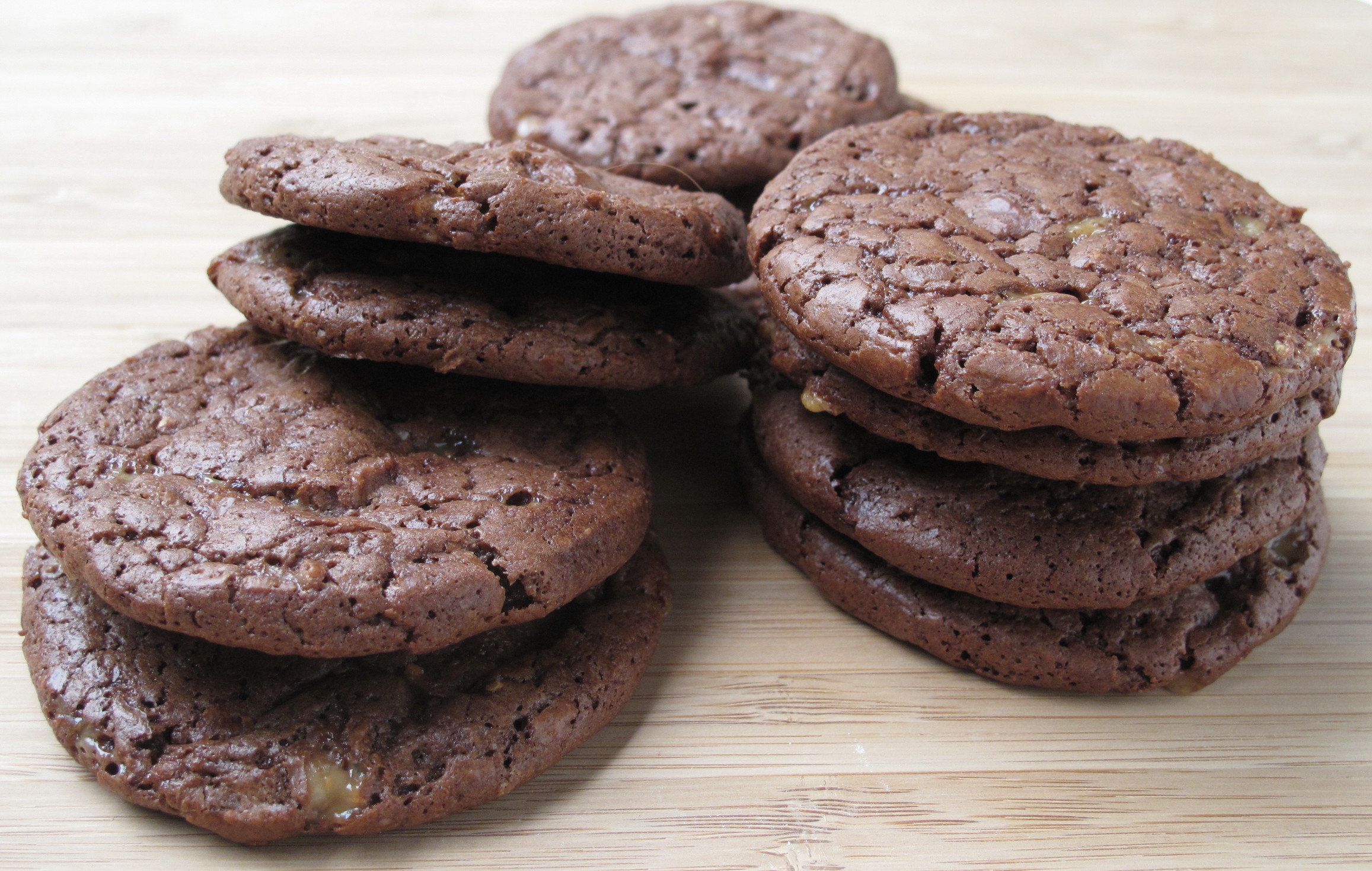 Chocolate Toffee Cookies piled on brown wood cutting board.