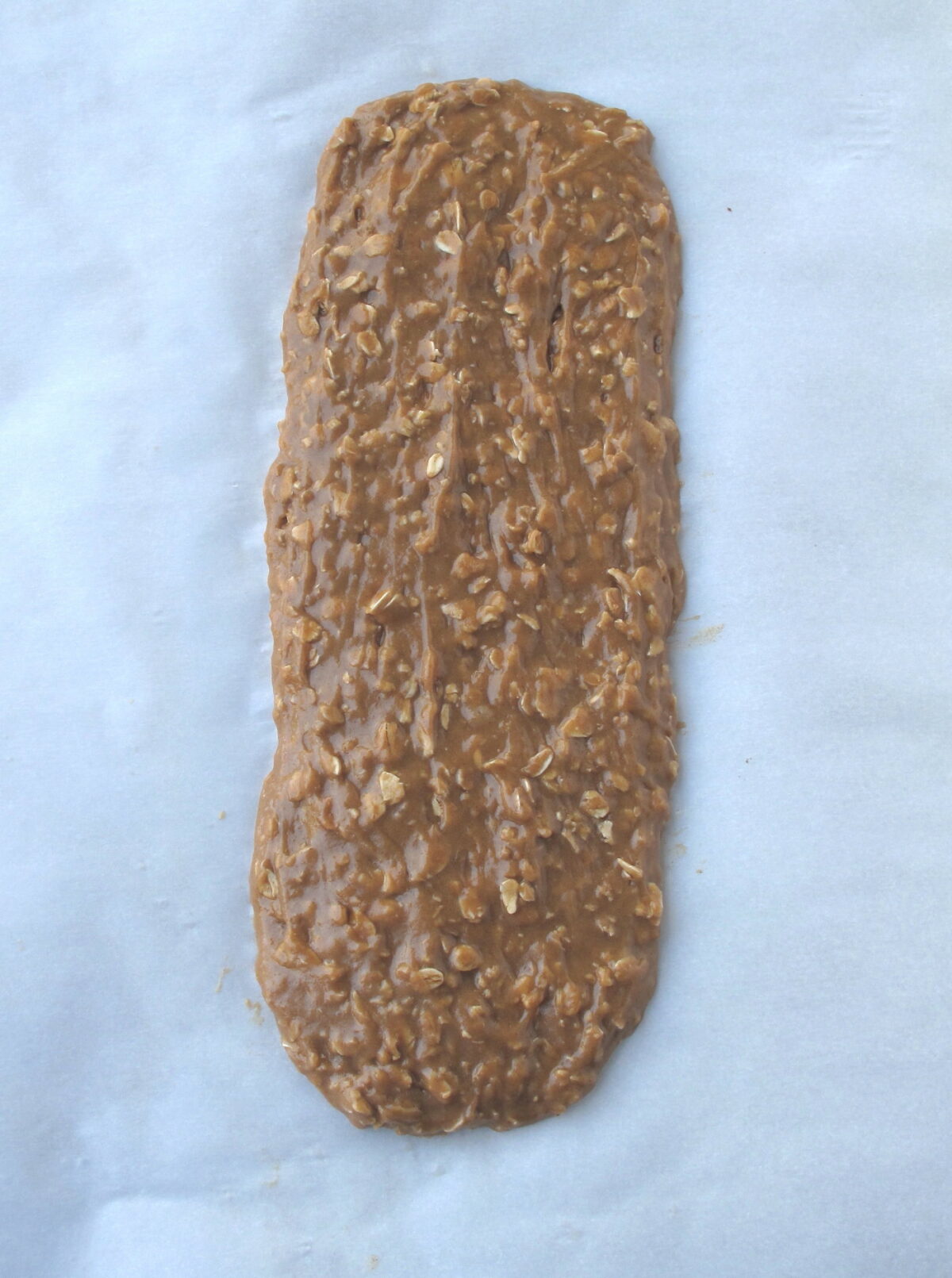 Biscotti batter log spread on a parchment lined baking sheet.