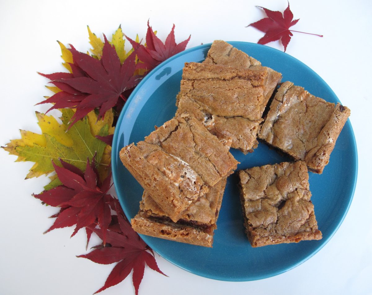 Chewy Chocolate Toffee Marshmallow Cookie Bars on a blue plate with colorful fall leaves.