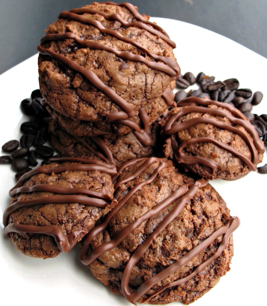 Brownie cookies with melted chocolate zigzags on top, on a white plate with espresso beans.