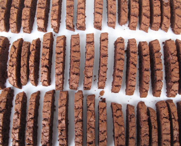 Sliced biscotti lined up in three rows on a baking sheet.