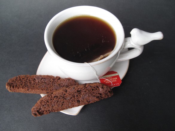 Biscotti on a saucer with a cup of tea from above.