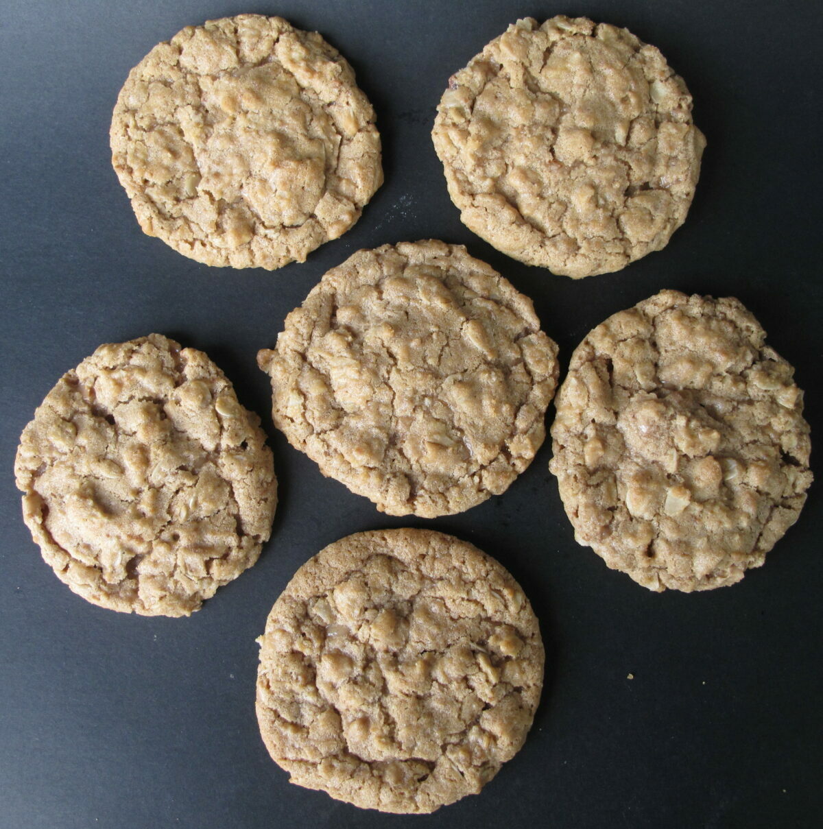 Six thin cookies with cracked and bumpy tops.