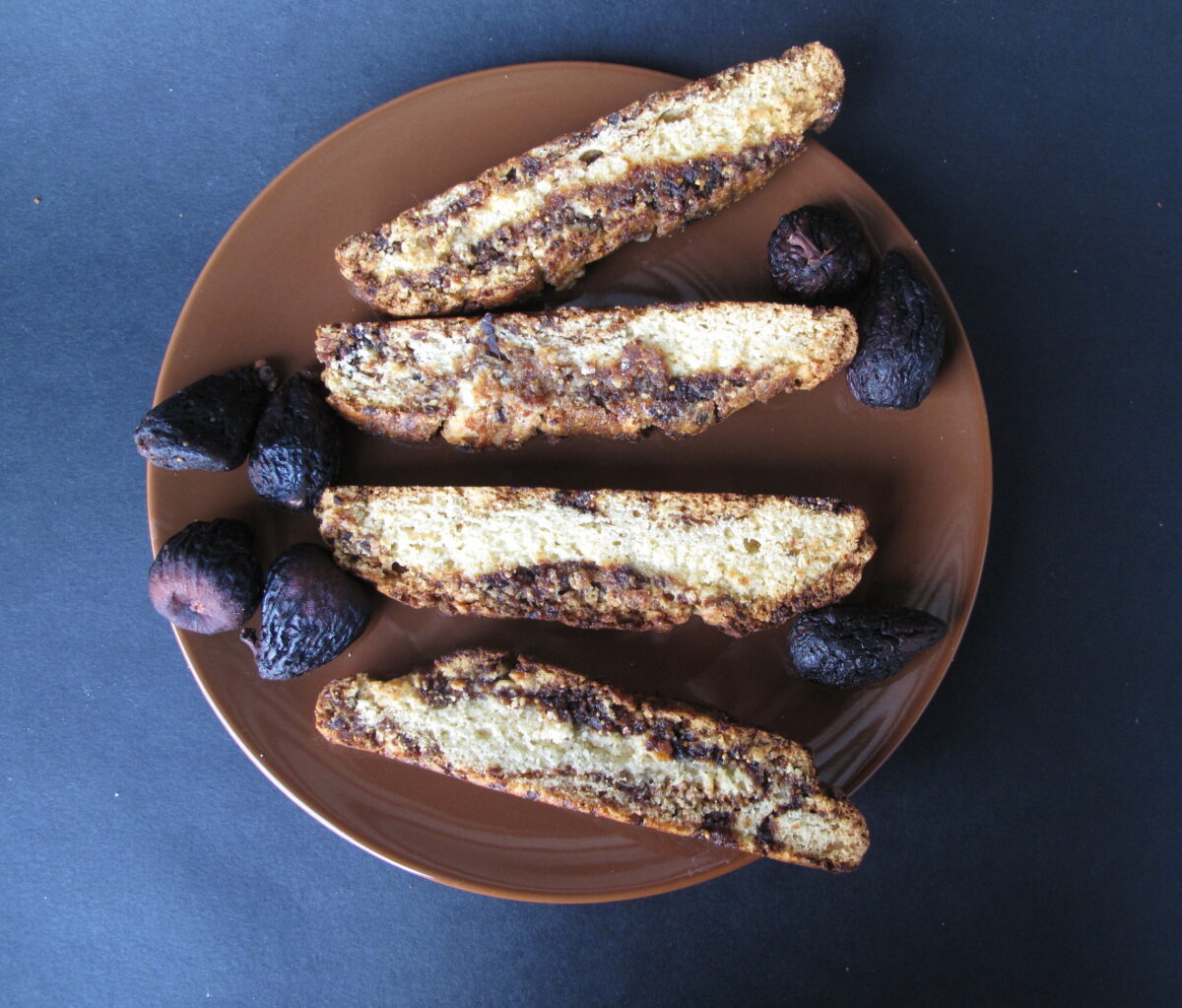 Biscotti and figs on a brown plate.