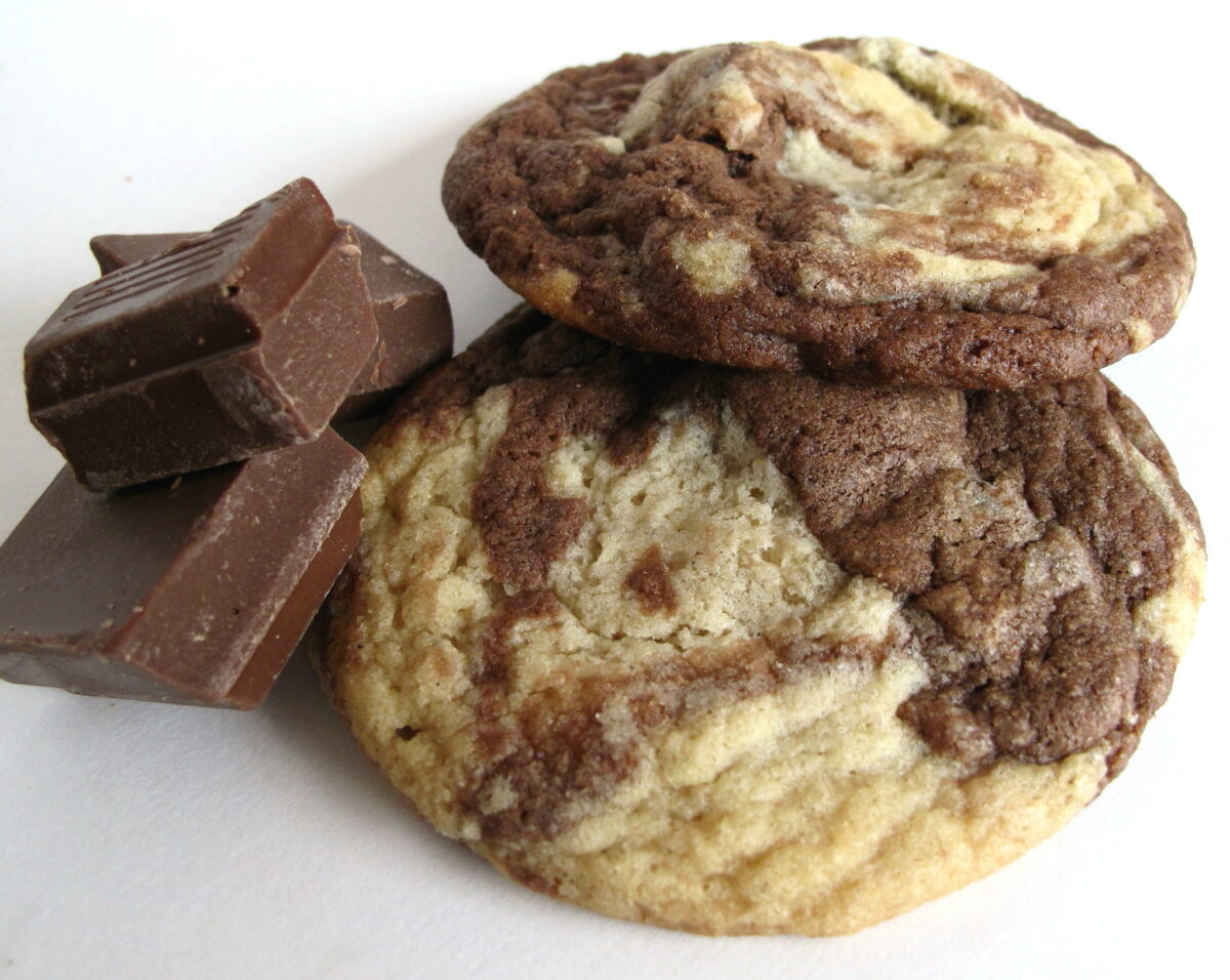 Marbled Chocolate Chunk Cookies on a white background with chunks of chocolate.