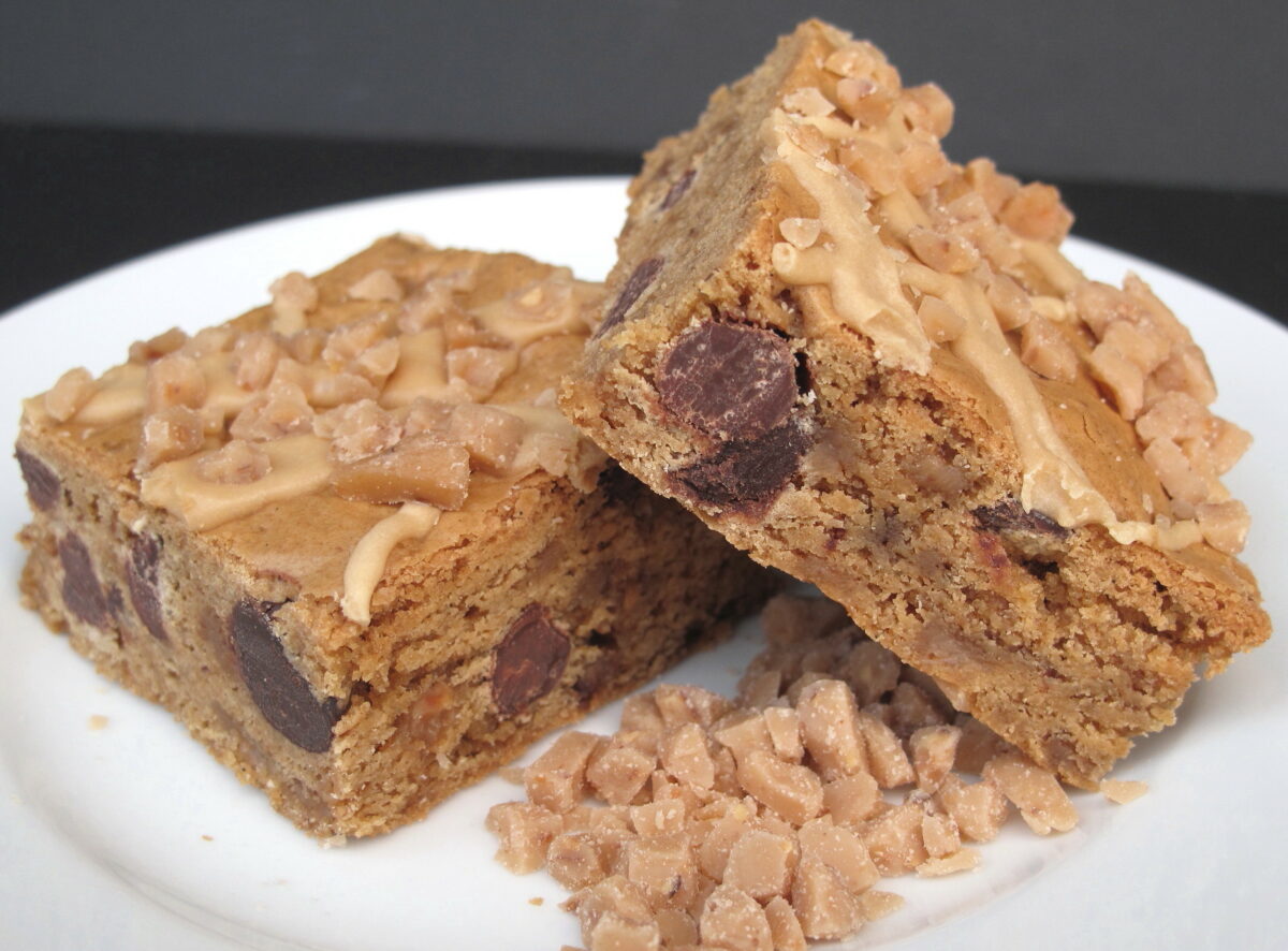 Two bars filled with chocolate chunks and toffee bits on a white plate.