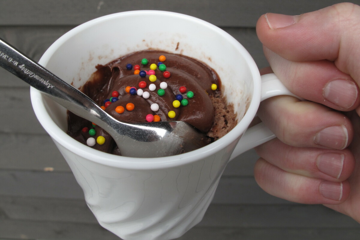 A hand holding a mug of cake