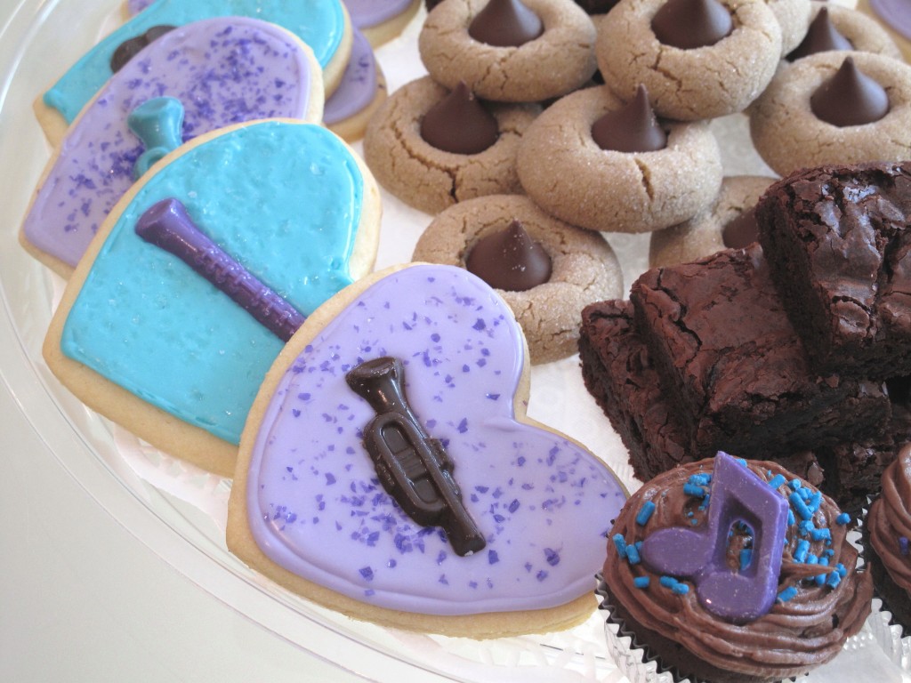 Closeup of heart shaped sugar cookie with lavender icing decorated with a chocolate molded trumpet.