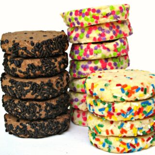 Two vanilla cookie stacks and one chocolate cookie stack with the edges covered in sprinkles.