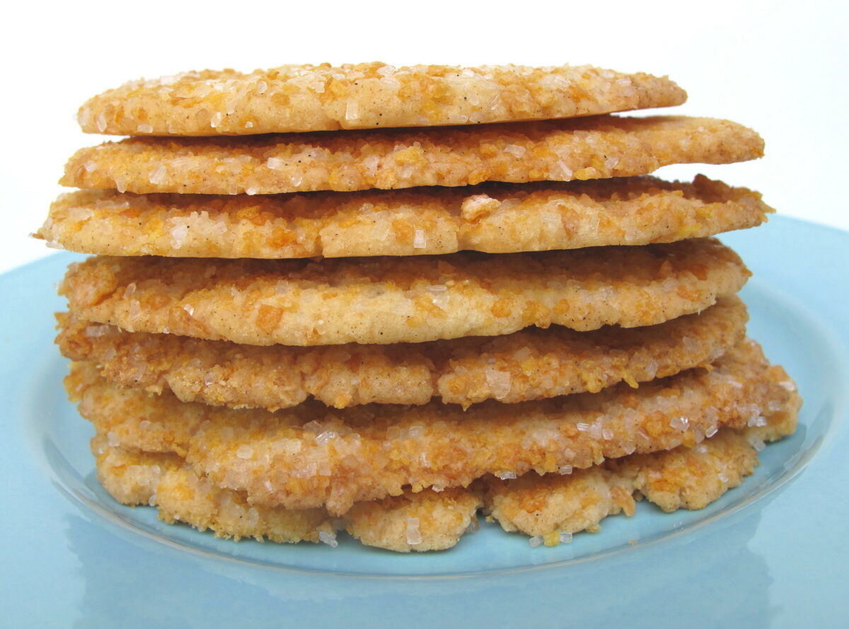 Frosted Flakes Sugar Cookies stacked on blue plate showing thin, crisp edges.