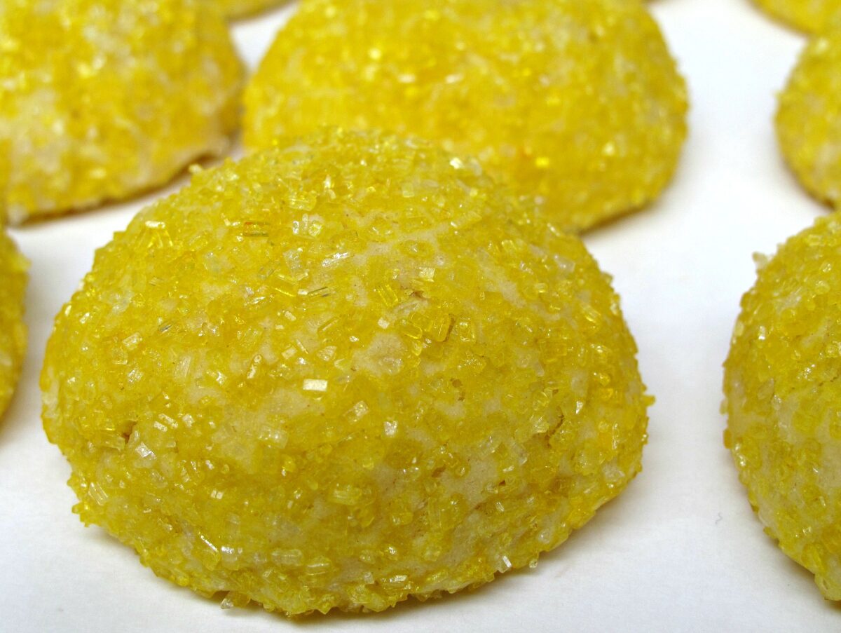 Closeup of domed cookie coated in yellow sparkling sugar.