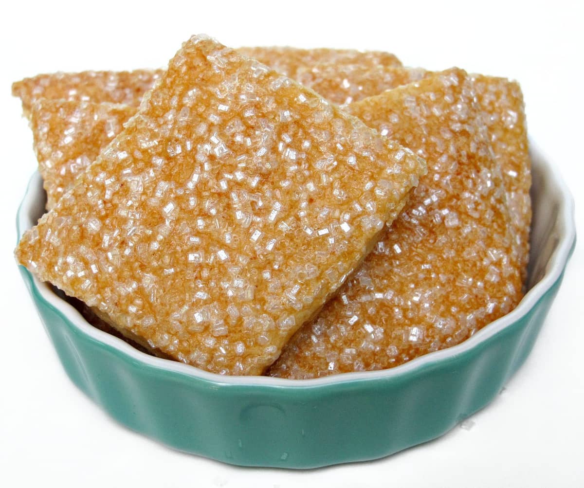 A bowl full of square pastry dough cookies coated in sparkling sugar.