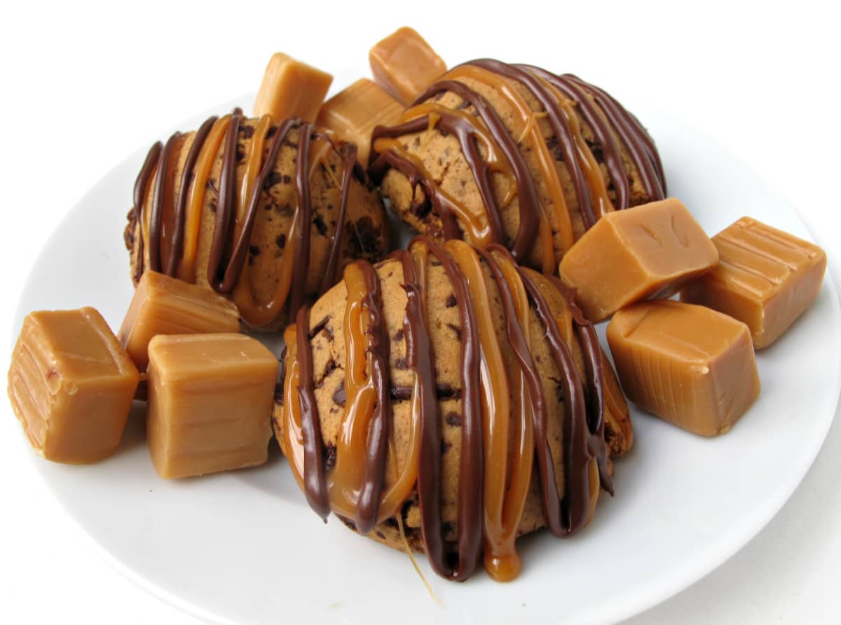 Three Caramel Chocolate Cookies on a white plate with caramel  candy squares. 