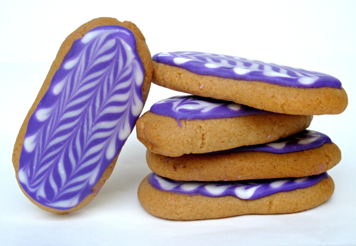 Honey Jumbles biscuits with purple icing in a stack.