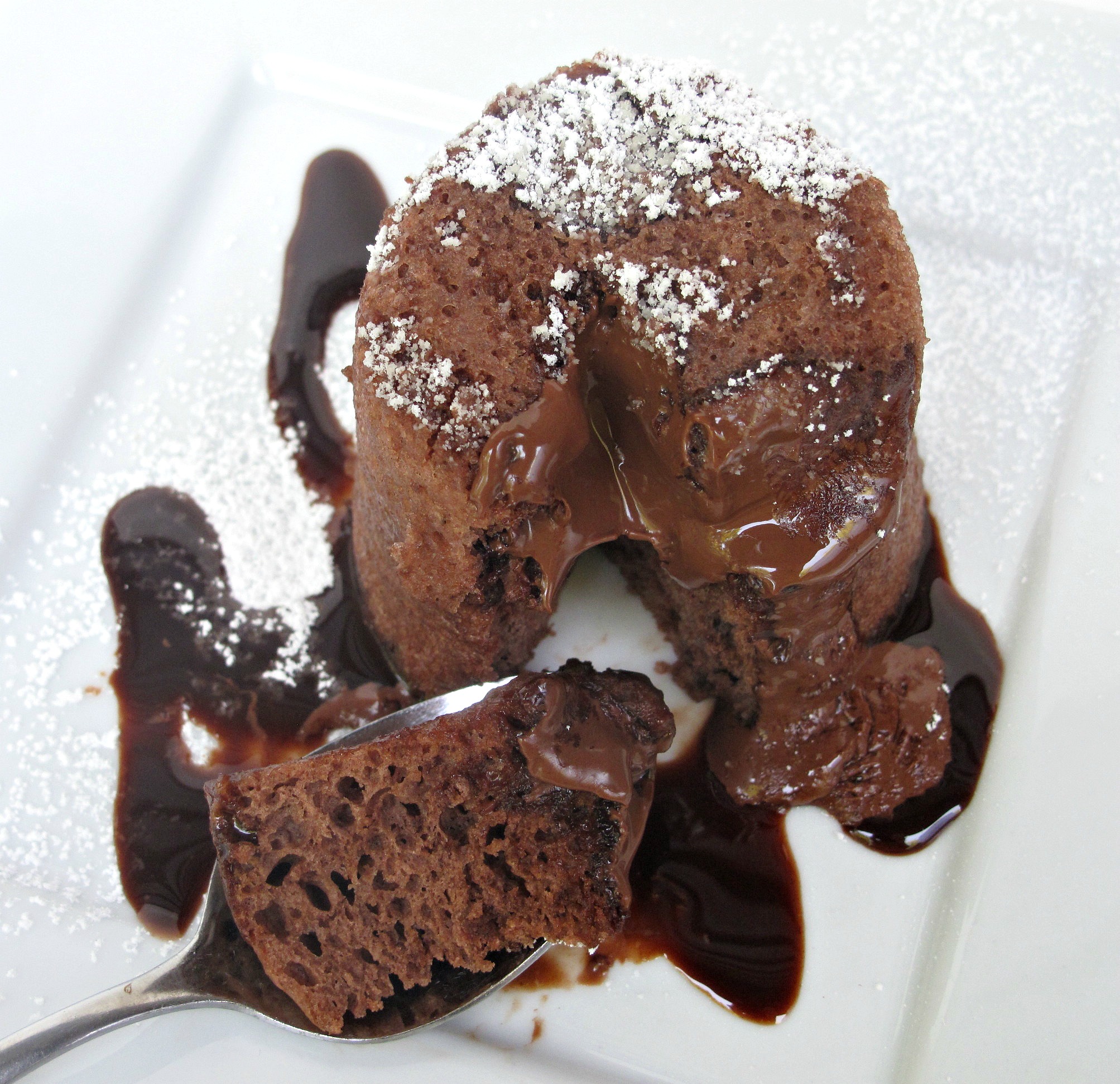 Molten Lava Mug Cake on plate with spoon full of cake and melted chocolate.