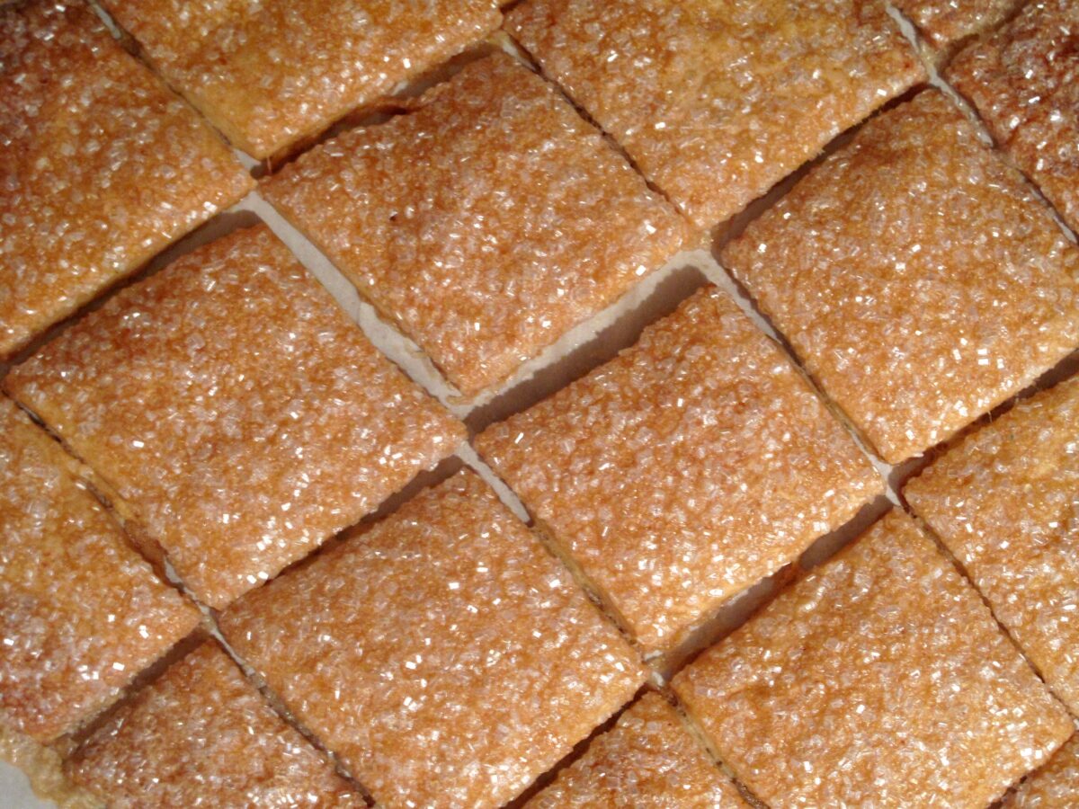 Rows of square cookies coated in white decorating sugar.