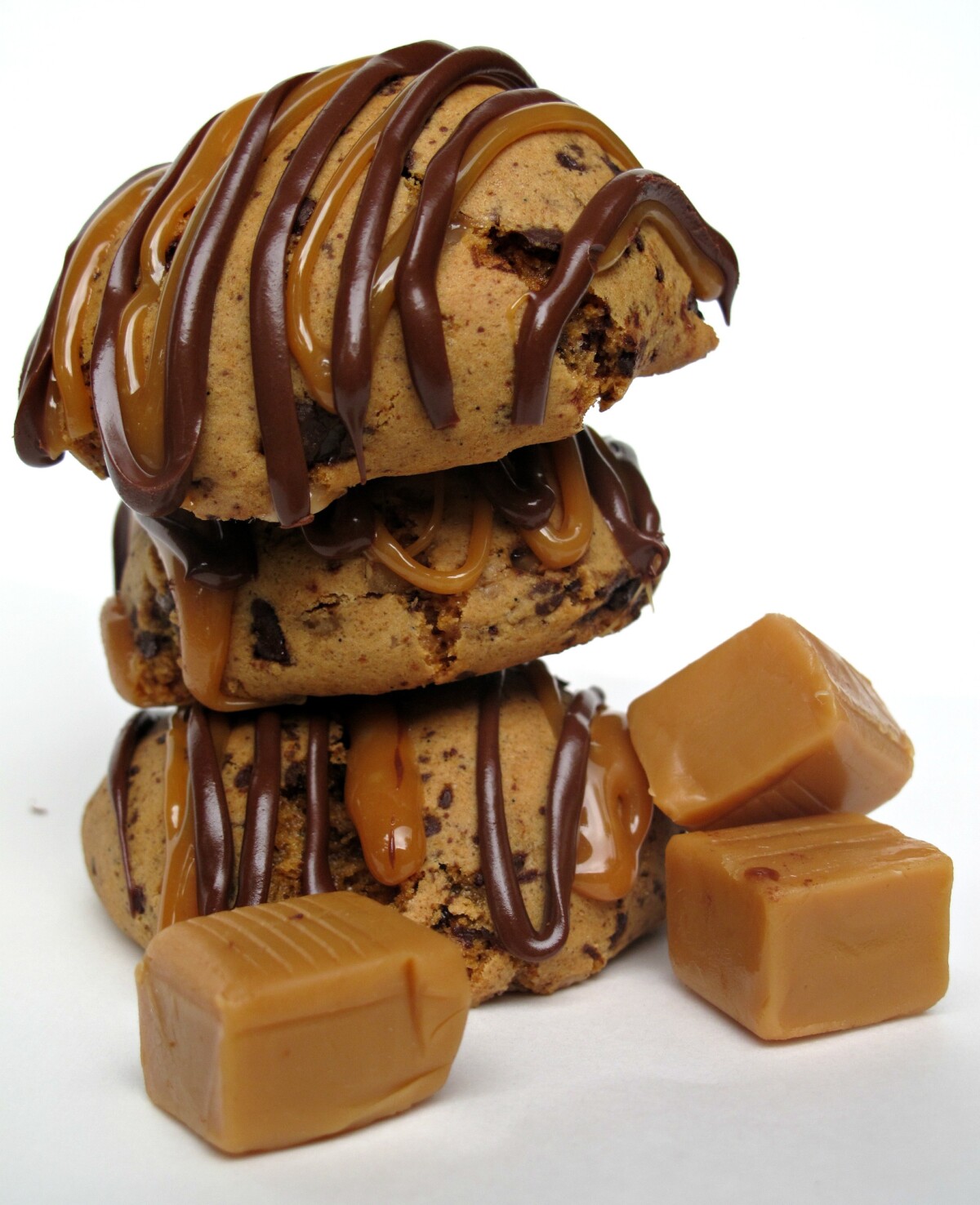 Stack of three cookies with zigzags of chocolate and caramel over the rounded tops.