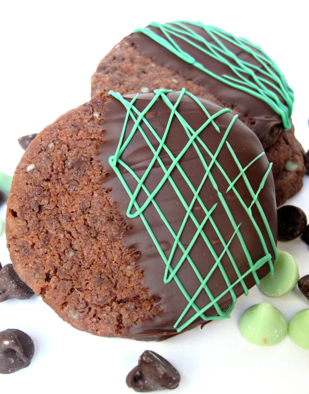 Closeup of a chocolate cookie dipped in chocolate with melted green mint chocolate drizzle.