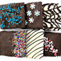 Chocolate covered graham crackers decorated with sprinkles and drizzle.
