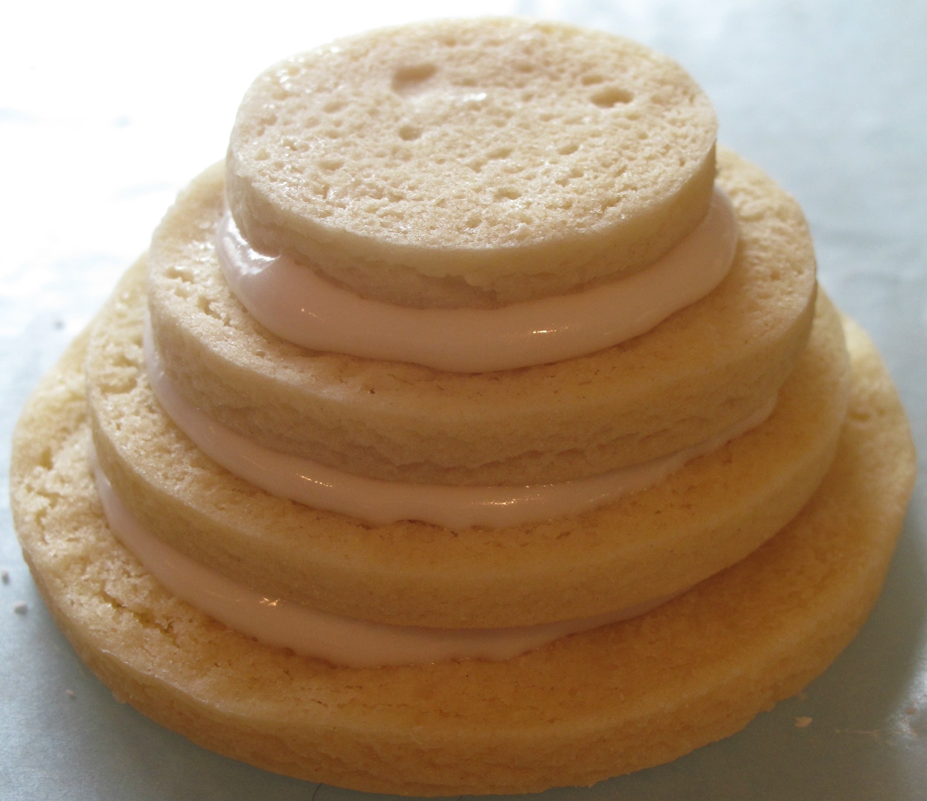 A stack of cookies attached together with corn syrup icing between layers.