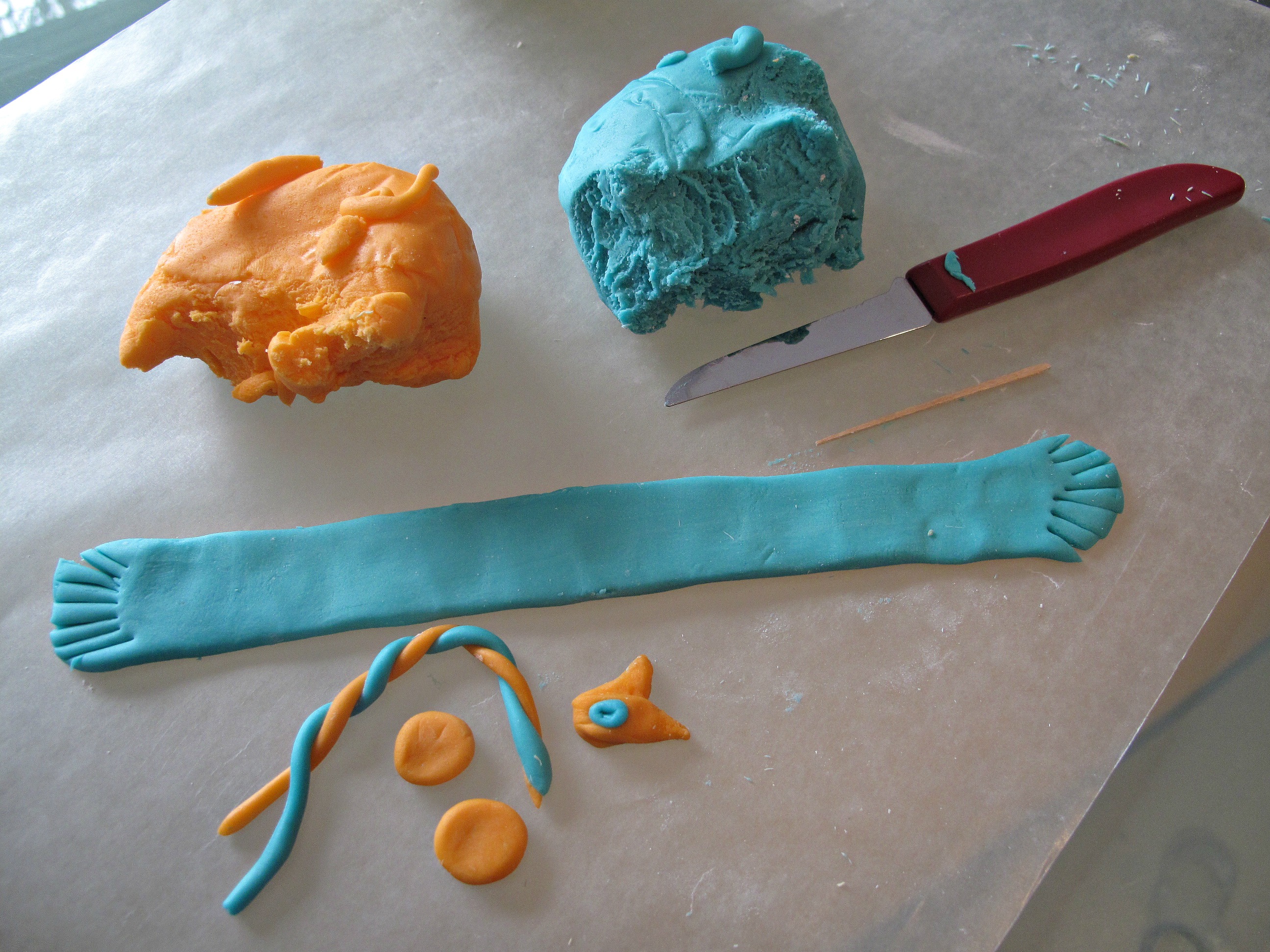 Colored fondant formed into a fringed scarf and pieces for earmuffs.