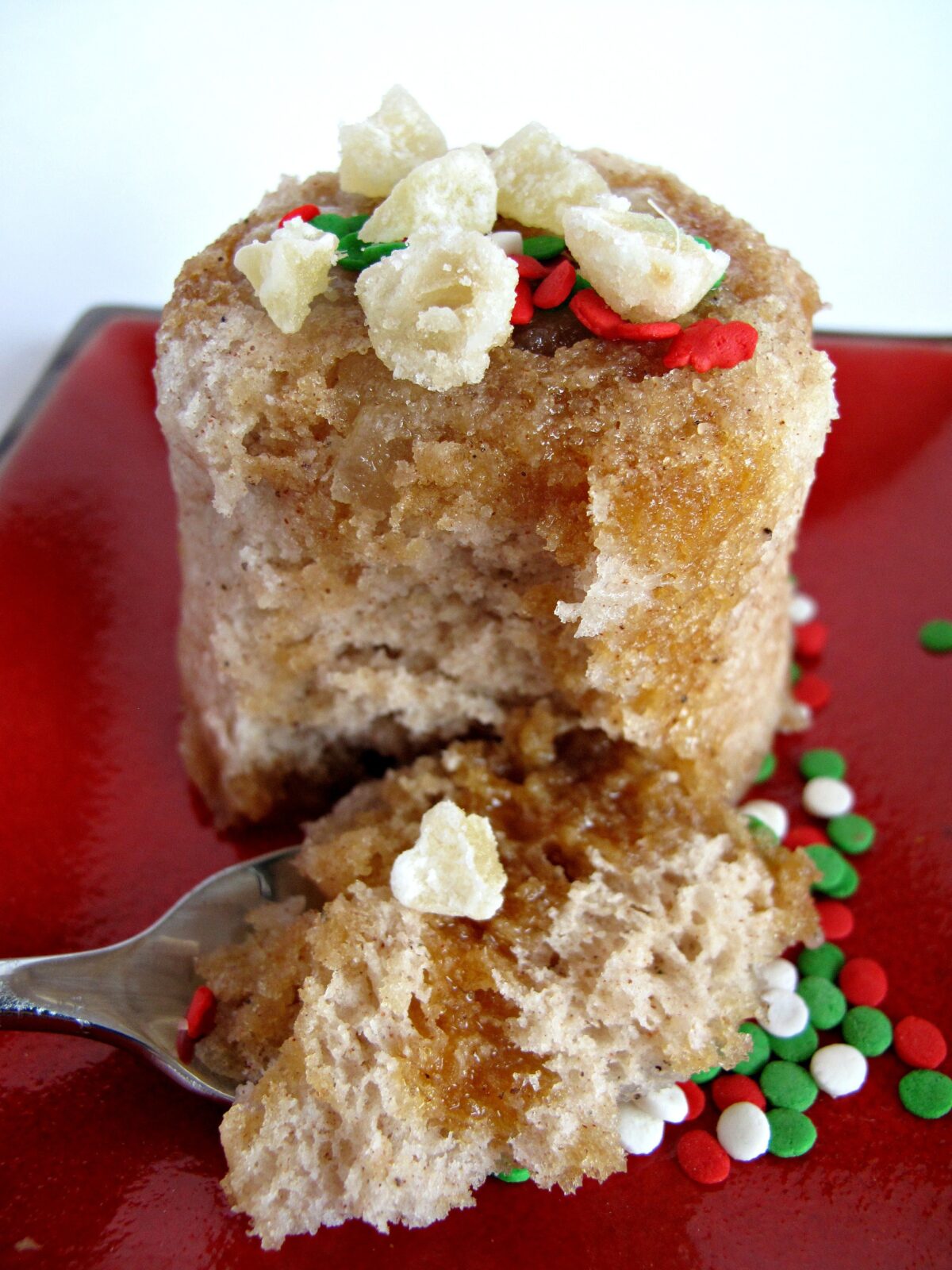 A spoonful of Gingerbread Mug Cake in front of the mug cake on a plate.
