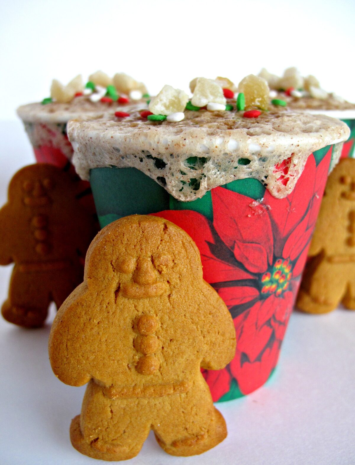 Gingerbread cookie in front of a  Gingerbread Mug Cake in a poinsettia paper cup.