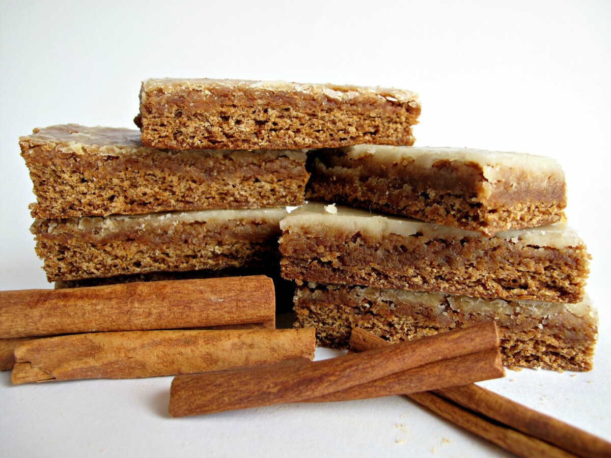 Two stacks of iced Lebkuchen bars next to some cinnamon sticks.