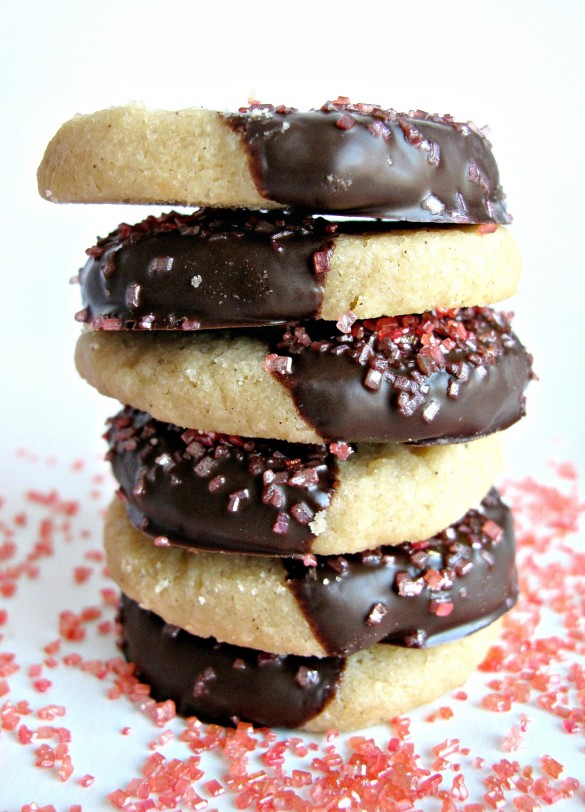Chocolate-Dipped Peach Tea Shortbread Cookies stacked to show one half of each cookie is dipped in chocolate and sprinkled with peach colored sugar.