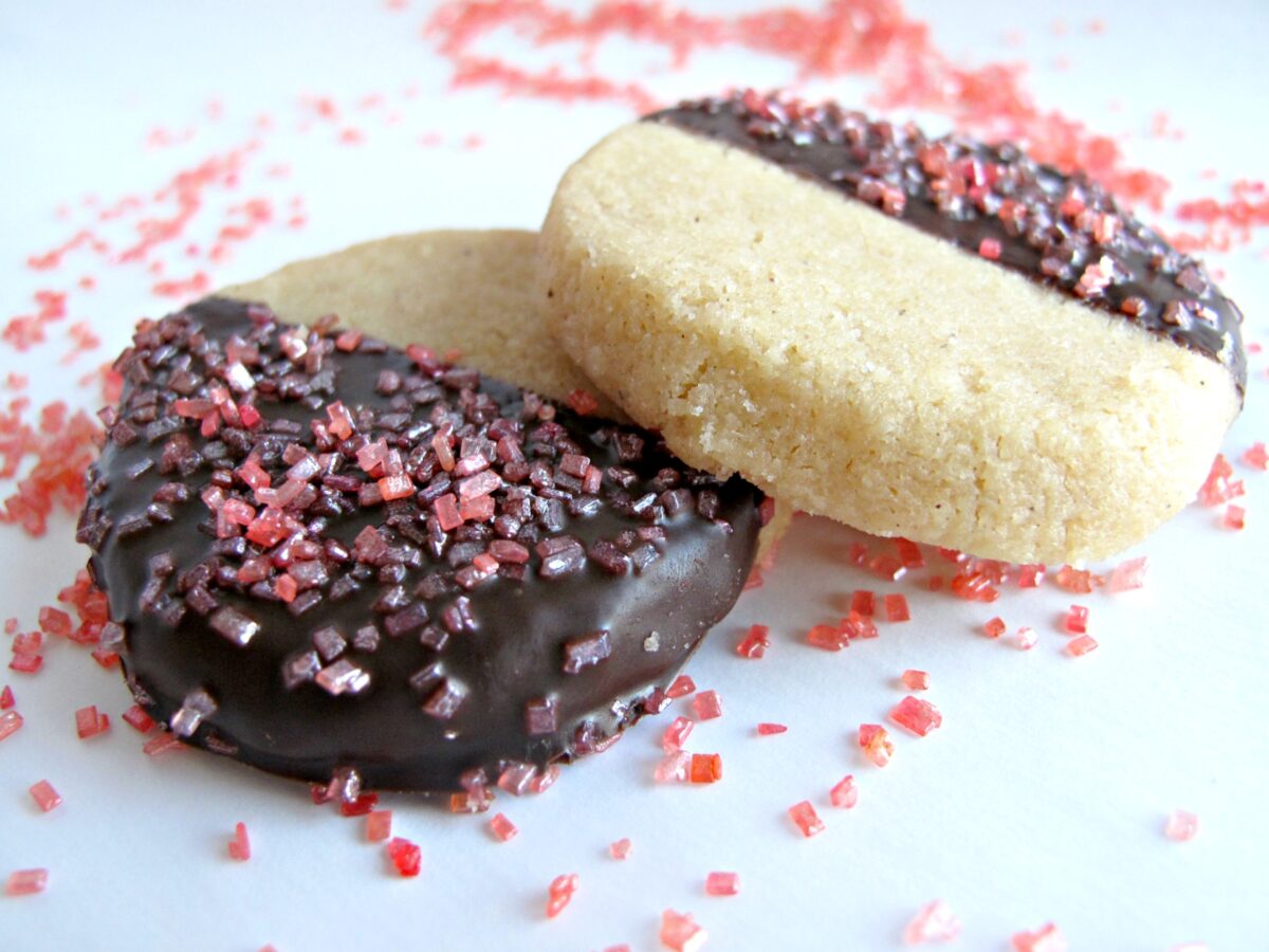 Two chocolate dipped shortbread cookies with large crystal sugar sprinkles.