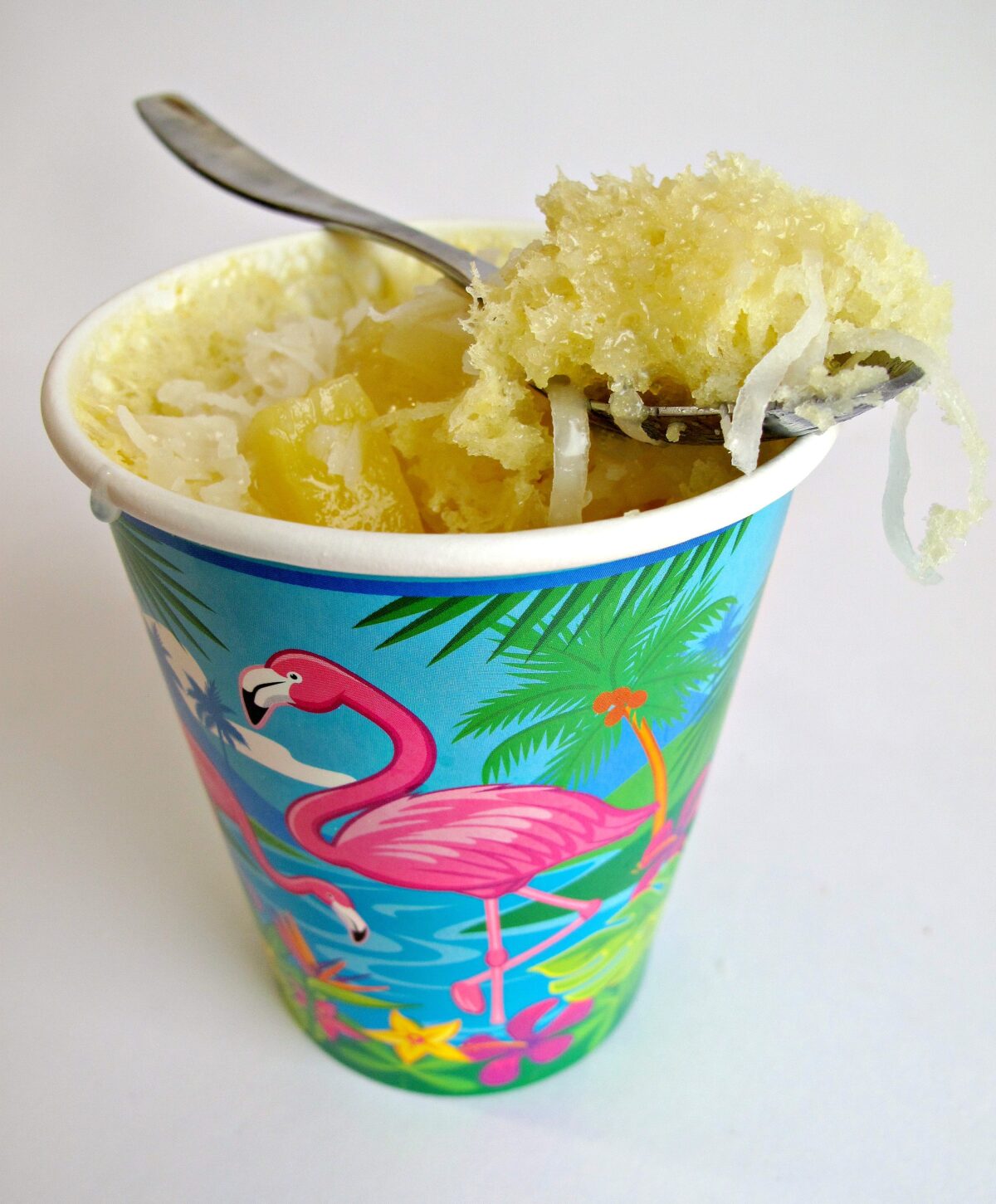 Piña Colada Cake in a paper cup with a spoon on top.