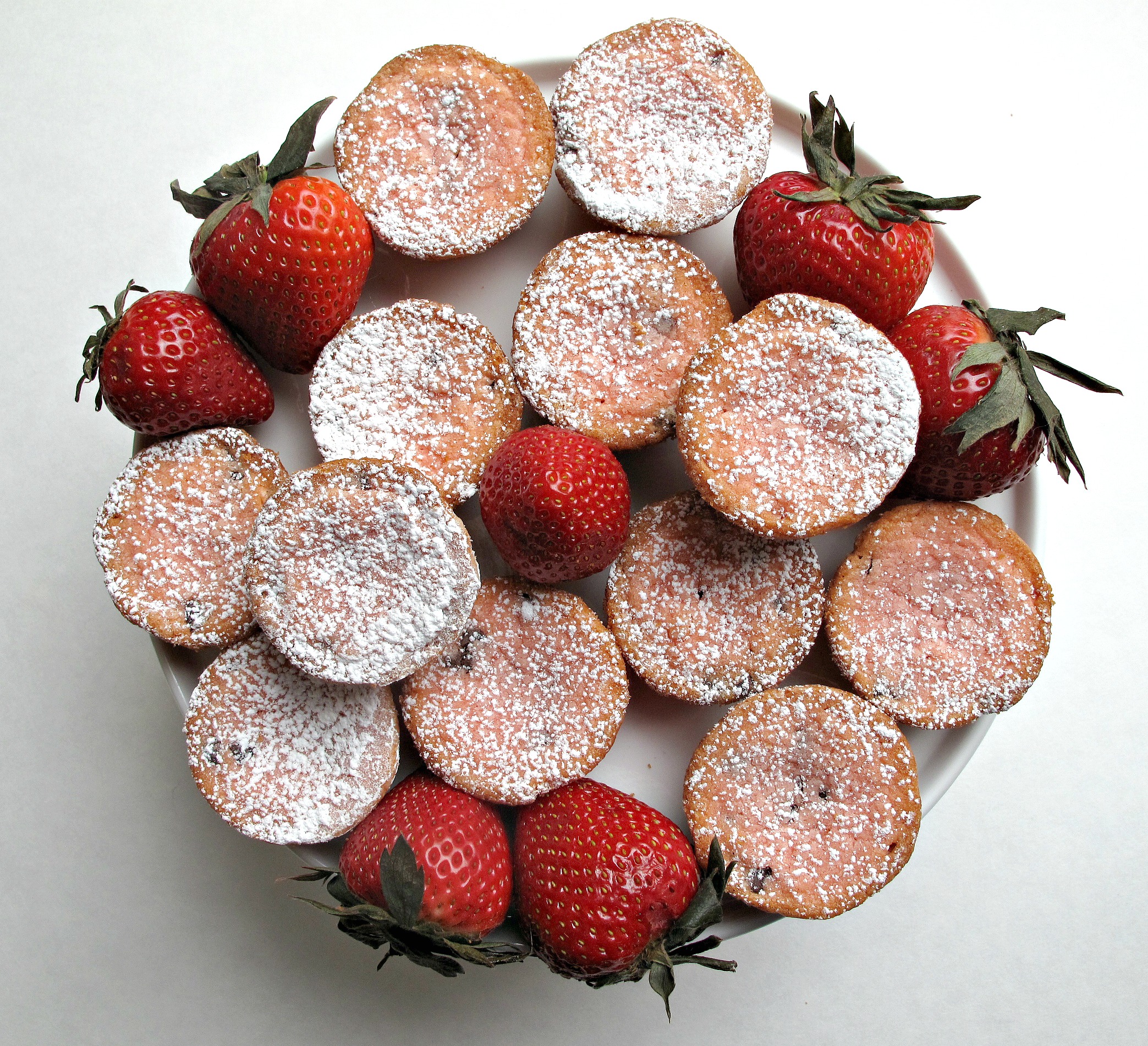 Blondie Bites topped with powdered sugar with large red strawberries on a round platter.