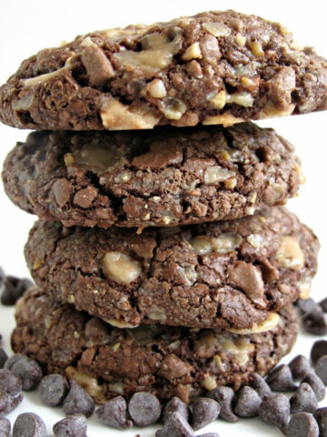 Stack of thick chocolate cookies with toffee bits.