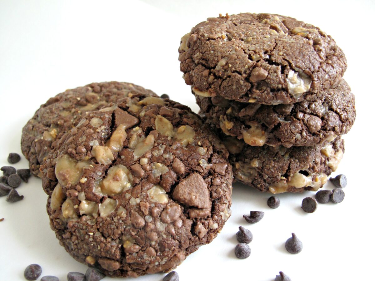 Cookies in two piles on a white surface with chocolate chips.
