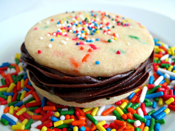 One Funfetti Sandwich Cookie from the side showing the two cookies sandwiching the piped on chocolate frosting.