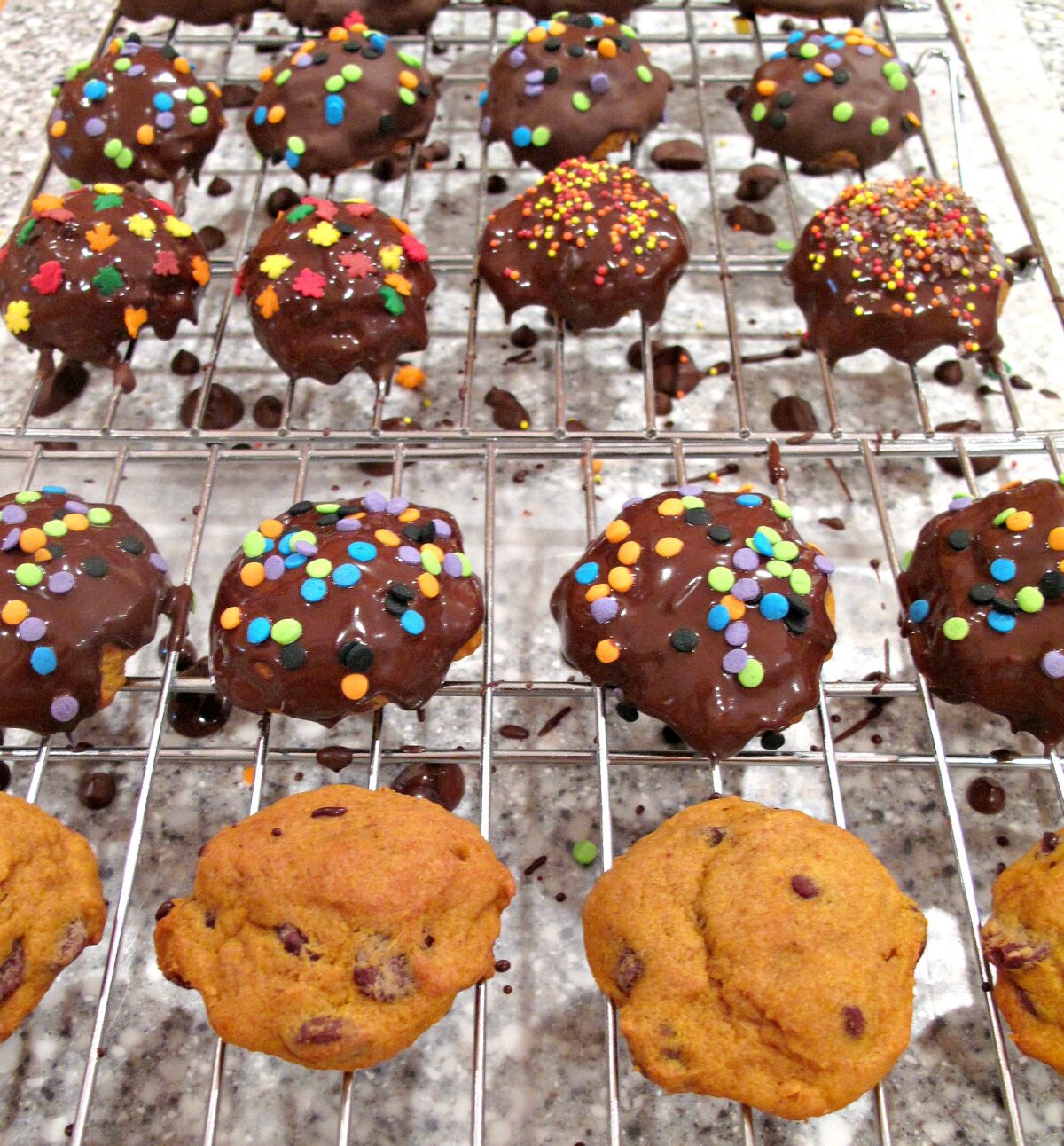 Cookies on a wire rack after chocolate coating and sprinkles are applied.