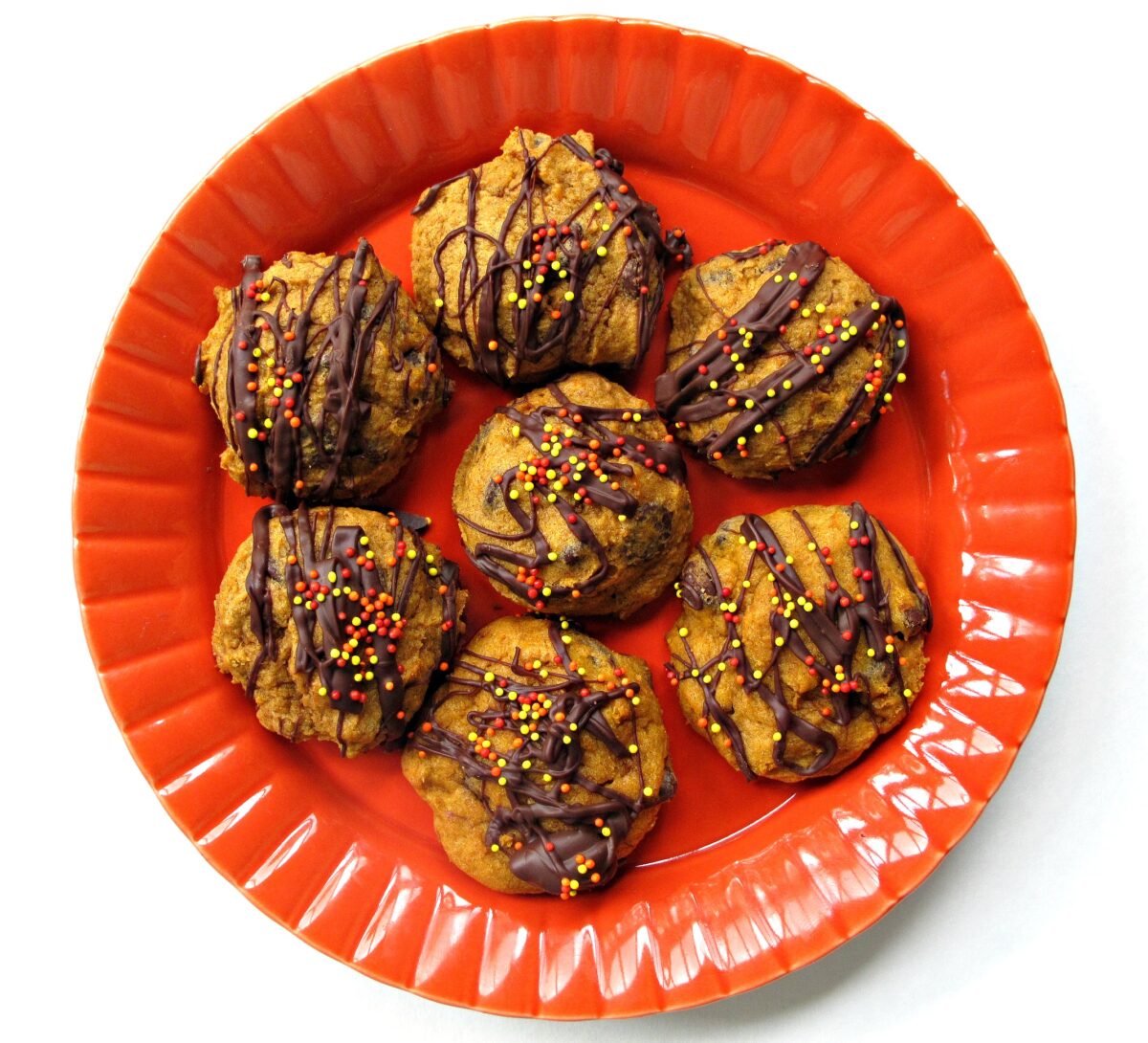 Chocolate drizzled on an orange plate.