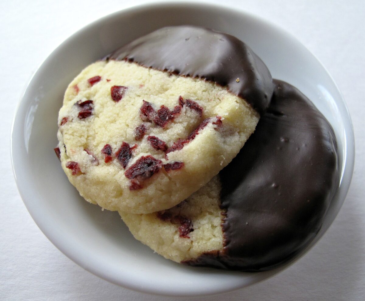 Two Cranberry Orange shortbread cookies in a small bowl..
