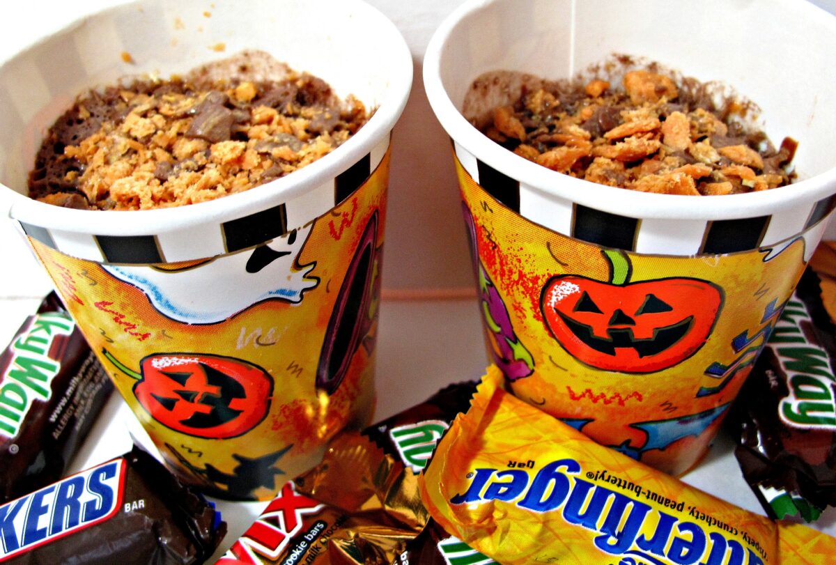 Cake mix Mug Cake made in paper Halloween cups with chopped mini candy bars.
