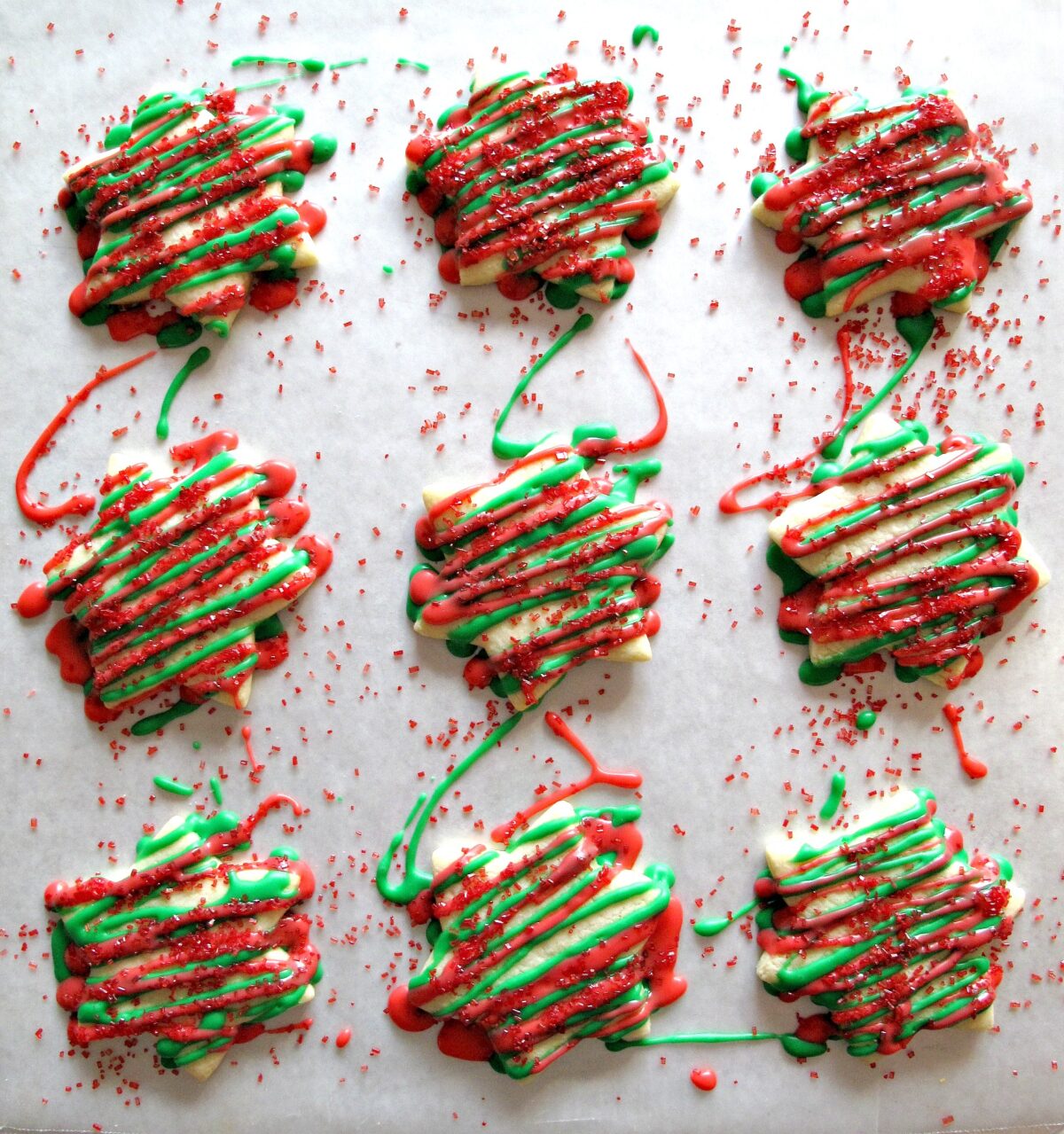 Star cookies decorated with red and green icing zigzags and red sugar.