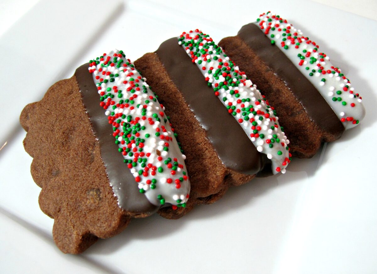Three chocolate dipped, rectangle cookies on a white plate.