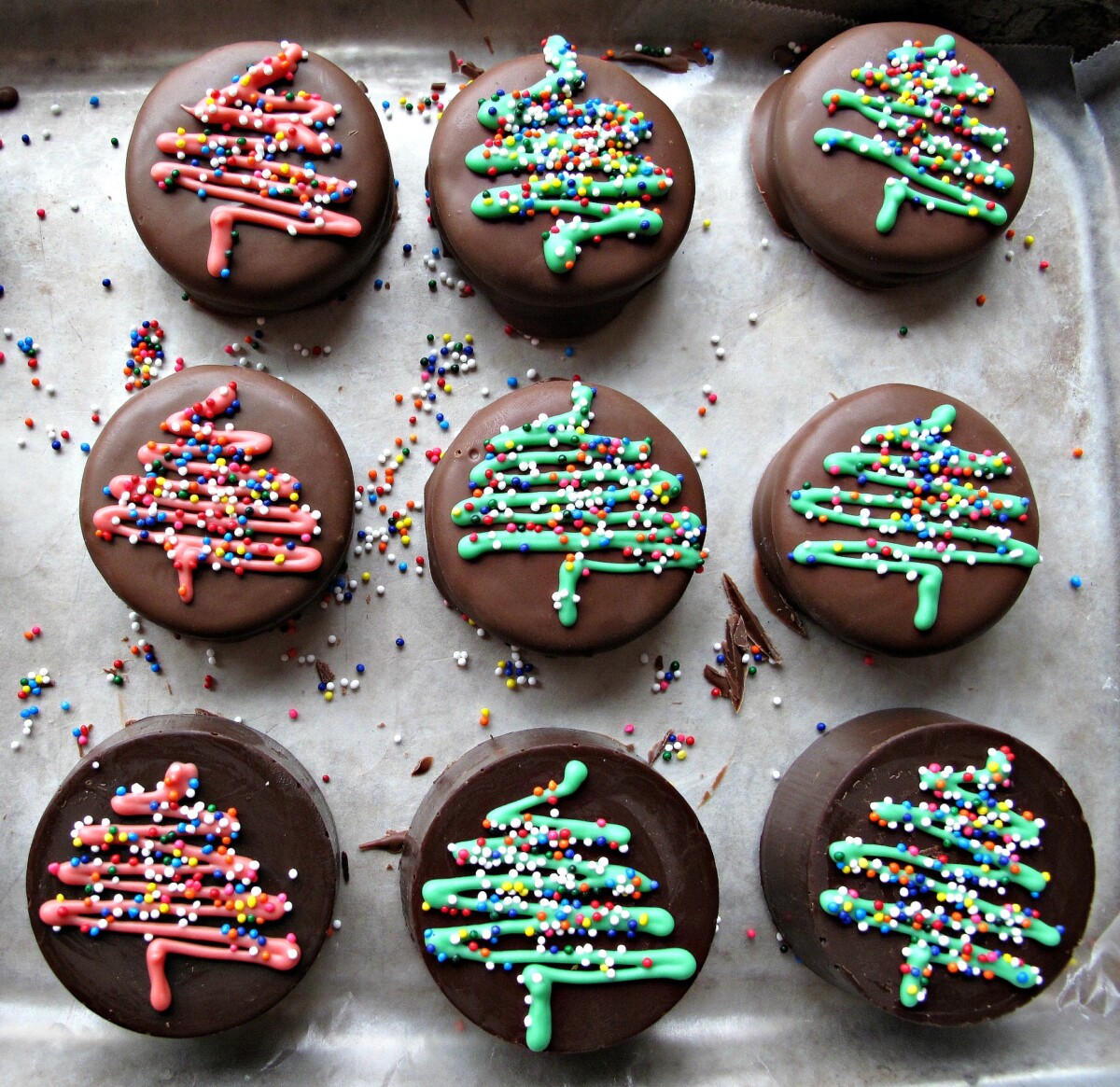 Chocolate covered oreos with a red or green zigzag Christmas tree design topped with nonpareil sprinkles.