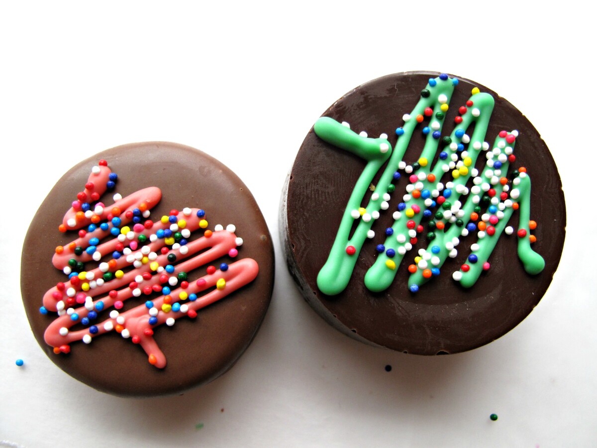 Two chocolate covered Oreos with a zigzag Christmas tree design in green and red.