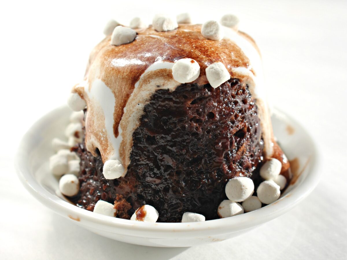Hot Chocolate Mug Cake turned onto a plate and topped with melted marshmallow and mini marshmallows.