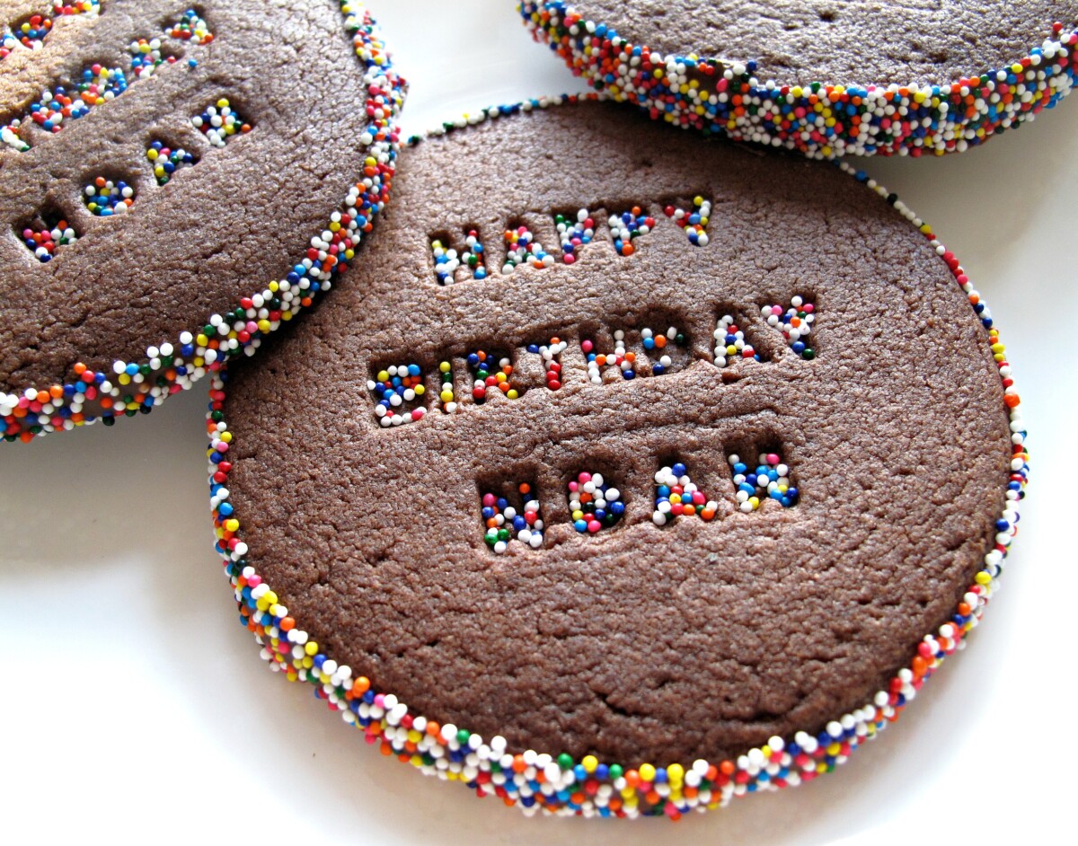 Three Celebration Sprinkle Cookies decorated with imprinted words and sprinkle coated edges.