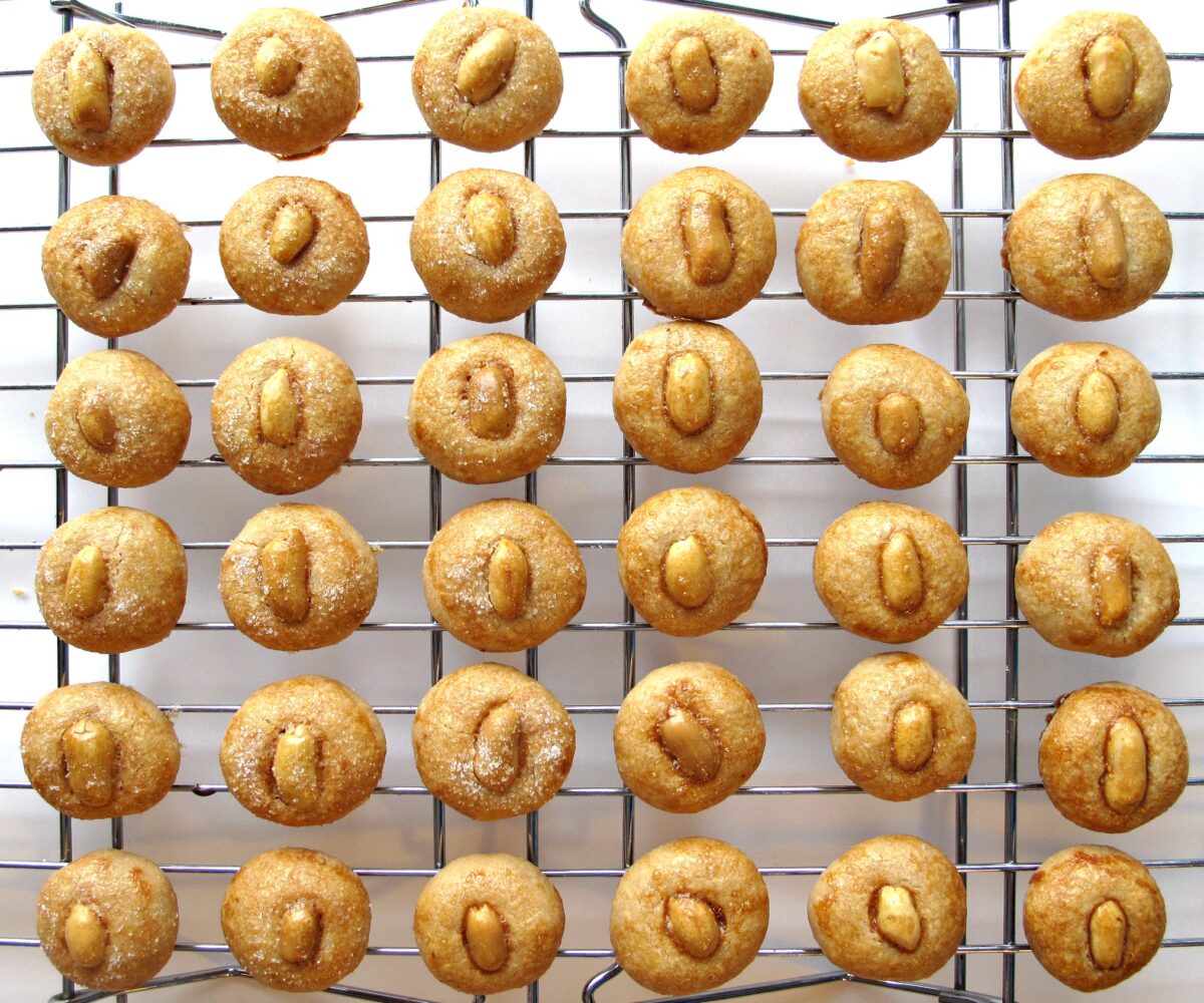 Peanut topped cookies lined up on a wire cooling rack.
