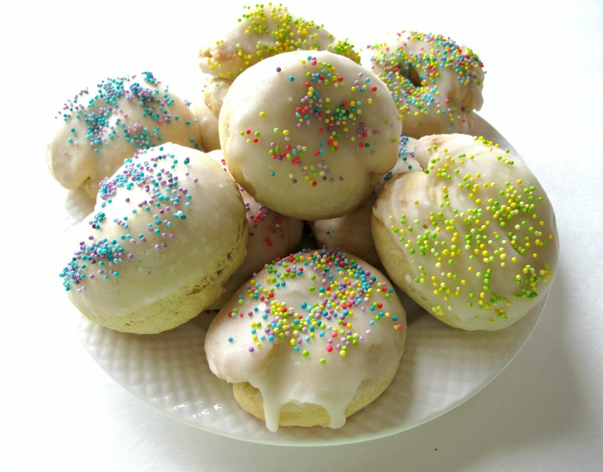 Ball shaped cookies covered with glaze and pastel nonpareil sprinkles.